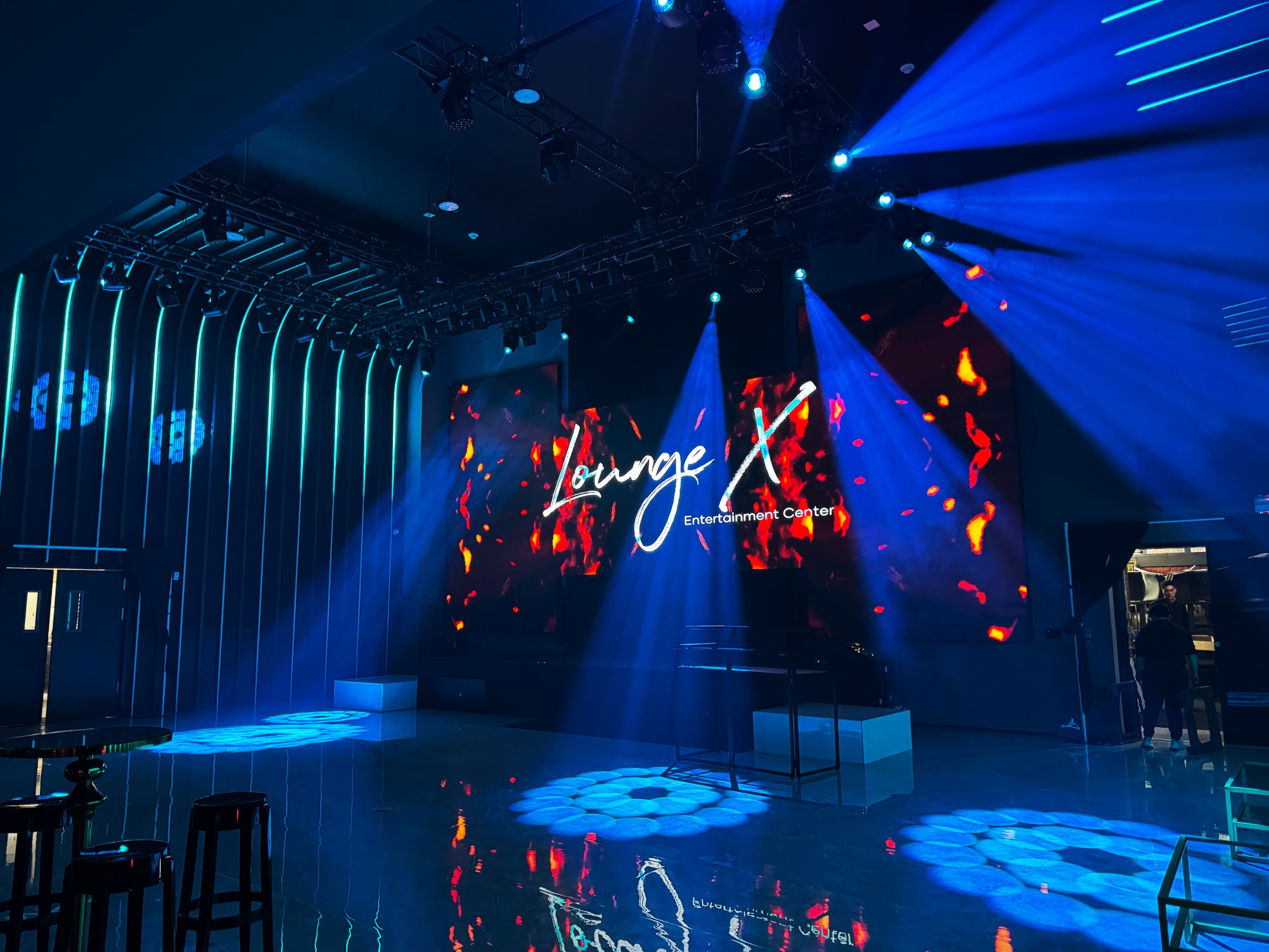 Lounge X event stage with LED walls, blue beams, and branded digital visuals
